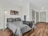 Modern bedroom with sleek hardwood floors, elegant gray bedding, chic artwork, and stylish lighting.