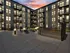 Modern apartment complex with beautifully lit courtyard, featuring stylish outdoor seating and sunset views.