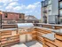 Chic rooftop patio with modern barbecue grill surrounded by urban views and contemporary apartment buildings.
