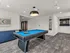 Elegant recreational room featuring a modern pool table with bright blue felt and wall-mounted dartboard, perfect for entertainment and relaxation.