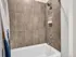 Elegant bathroom with modern beige tiles, a sleek bathtub, and a stylish showerhead.