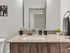 Elegant bathroom with granite countertop, modern fixtures, and sleek mirror, enhanced by subtle decor and a potted plant.