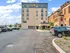 Modern apartment building with sleek architecture and ample parking space, featuring lush landscaping in a vibrant neighborhood.