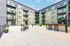 Modern apartment courtyard with stylish outdoor seating, lush green spaces, and a community grilling area, perfect for relaxation and social gatherings.