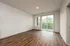 Bright, modern apartment with elegant hardwood floors, large windows, and inviting balcony access overlooking lush greenery.