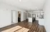 Bright and modern open-concept living area with elegant wood flooring, showcasing a sleek kitchen with stainless steel appliances and a spacious island.