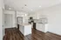 Modern kitchen with sleek white cabinets, granite countertops, and stainless steel appliances, complemented by elegant hardwood flooring and stylish pendant lights.