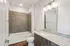 Elegant bathroom with sleek granite countertop, large mirror, and modern bathtub in a stylish apartment.