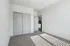 Bright, inviting bedroom with plush carpet and modern double-door closet, leading into a sleek, airy kitchen area.