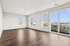 Expansive modern living room with sleek hardwood floors and abundant natural light, offering stunning city views through large windows.