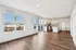 Bright open-concept apartment showcasing sleek hardwood floors, a modern kitchen with stainless steel appliances, and large windows offering city views.