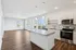 Modern open-plan apartment featuring sleek kitchen, granite countertops, and abundant natural light through large windows.