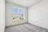 Bright empty room with plush carpeting and a large window offering stunning cityscape views.