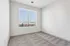 Bright and airy bedroom with large window and soft carpeting, offering charming views of the cityscape.