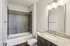 Modern bathroom with sleek tile work, elegant granite countertop, and contemporary lighting.