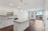Modern open-concept kitchen and living area with sleek cabinetry, granite countertop island, and bright natural light from large windows and balcony.