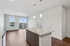 Bright and modern open-concept kitchen with granite countertops and elegant pendant lighting leading to a large balcony with city views.