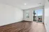 Bright and inviting apartment interior with large windows, modern wooden flooring, and sliding glass doors opening to a balcony.