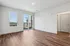 Bright and spacious room with elegant wood flooring, large windows, and balcony access offering plenty of natural light and modern living space.