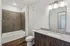 Modern bathroom featuring elegant granite countertops, sleek wood cabinetry, and a stylishly tiled shower area.