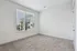 Bright and spacious bedroom featuring plush carpet and a large window with modern blinds showcasing a scenic urban view.