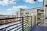 Modern apartment balcony view showcasing sleek railings, vibrant courtyard, and stylish building facade under a bright blue sky.