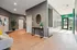 Modern apartment lobby with sleek hardwood floors, ambient lighting, and inviting seating area, leading to a bright, airy corridor.