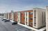 Modern apartment building featuring a sleek design with wood and brick facade, ample parking, and a serene suburban setting.