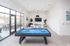 Luxury apartment game room with a sleek pool table, modern furniture, and large windows for abundant natural light.
