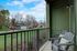 Charming balcony view featuring cozy seating, lush greenery, and a serene neighborhood backdrop.