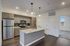 Modern kitchen with sleek gray cabinets, stainless steel appliances, and stylish pendant lighting over a granite-topped island.