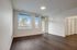 Bright and modern living area with dark hardwood floors, large windows for natural light, and a doorway leading to a serene outdoor view.