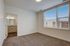 Bright and inviting bedroom with plush carpeting and large window offering abundant natural light, connected to a modern bathroom with sleek finishes.