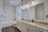 Elegant bathroom with dual sinks, granite countertops, modern lighting, and a bright atmosphere.
