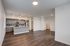 Modern apartment featuring an open-concept kitchen with sleek cabinetry and stainless steel appliances, highlighted by stylish pendant lighting and rich wood flooring.