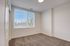 Bright, spacious bedroom with plush carpet and large sunlit window offering a serene view.