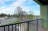 Charming apartment balcony offering a scenic view of lush greenery and vibrant neighborhood under a bright blue sky.