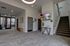 Modern apartment lobby featuring elegant decor with a wall-mounted TV, a stylish console table, and contemporary artwork. Bright and inviting space with access to a fitness room and stairway.