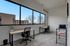 Bright, modern office space with large windows, two workstations, and sleek decor, offering serene outdoor views.
