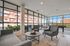 Modern and spacious living room with chic gray furniture, abundant natural light from floor-to-ceiling windows, and a vibrant urban view.