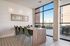 Bright and modern dining area featuring a sleek wooden table with green chairs, large windows offering natural light and views, and stylish patterned flooring.