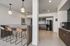 Modern kitchen area with sleek design, featuring stylish pendant lighting, a contemporary bar with leather stools, and vibrant green tile accents.