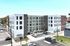 Modern multi-story apartment complex featuring sleek design and ample parking, set in a vibrant urban environment.