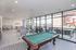 Modern community lounge with chic seating, pool table, and large windows offering vibrant city views.