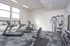 Modern fitness center with state-of-the-art exercise equipment, including treadmills, weight benches, and resistance machines, featuring large windows for natural light.