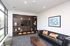 Modern living room with sleek black sofa, vibrant artwork, and elegant built-in shelving featuring decor and a TV.