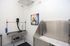 Modern pet grooming room featuring a sleek stainless steel wash station, drying table, and vibrant dog artwork, offering a fresh and inviting space.