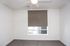 Modern and bright apartment bedroom with plush carpet and a large window for natural light.