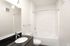 Sleek modern bathroom with glossy black countertop, elegant fixtures, and a pristine bathtub for ultimate relaxation.