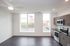 Modern apartment with sleek wood floors, expansive windows, and a contemporary kitchen featuring stainless steel appliances.